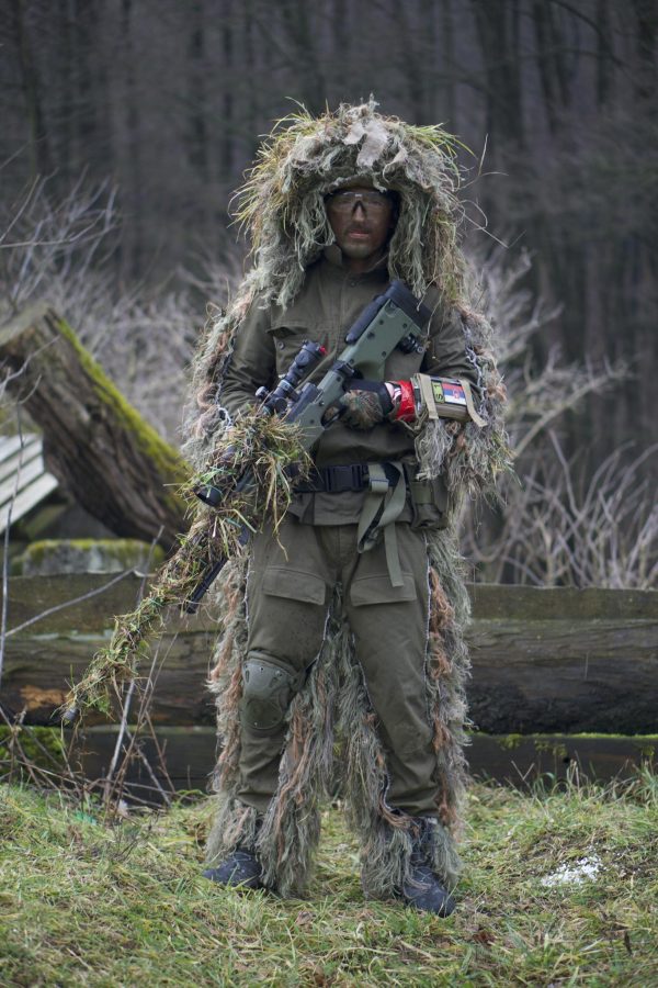 A Person in Green and Brown Camouflage Jacket Holding a Machine Gun