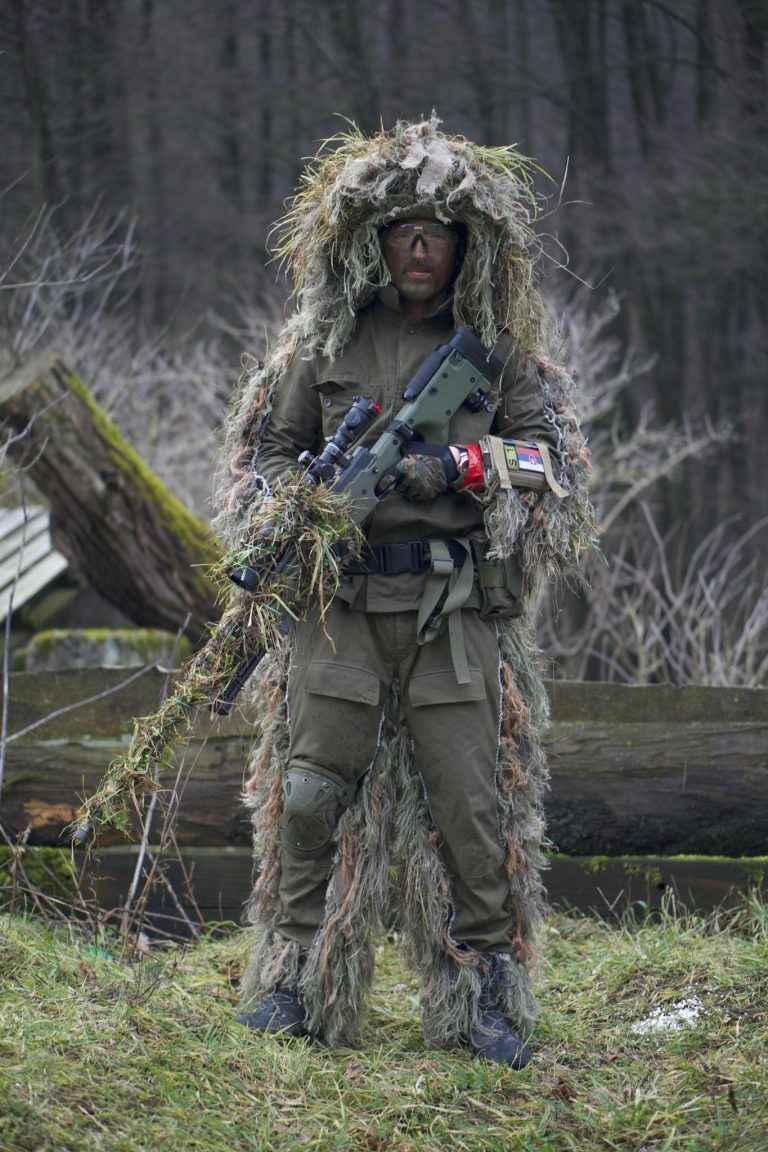 A Person in Green and Brown Camouflage Jacket Holding a Machine Gun
