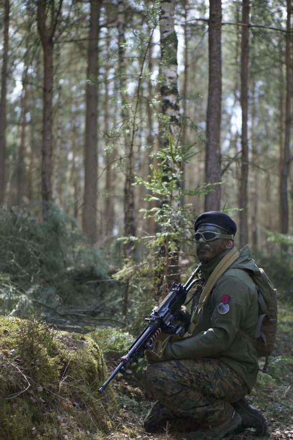 Man in Green Jacket Holding a Black Rifle in Forest